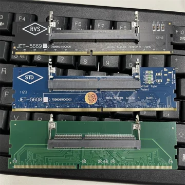 Three vintage RAM expansion cards laid across a laptop keyboard, showing gold-edge connectors and blue/green circuit boards with white labels.