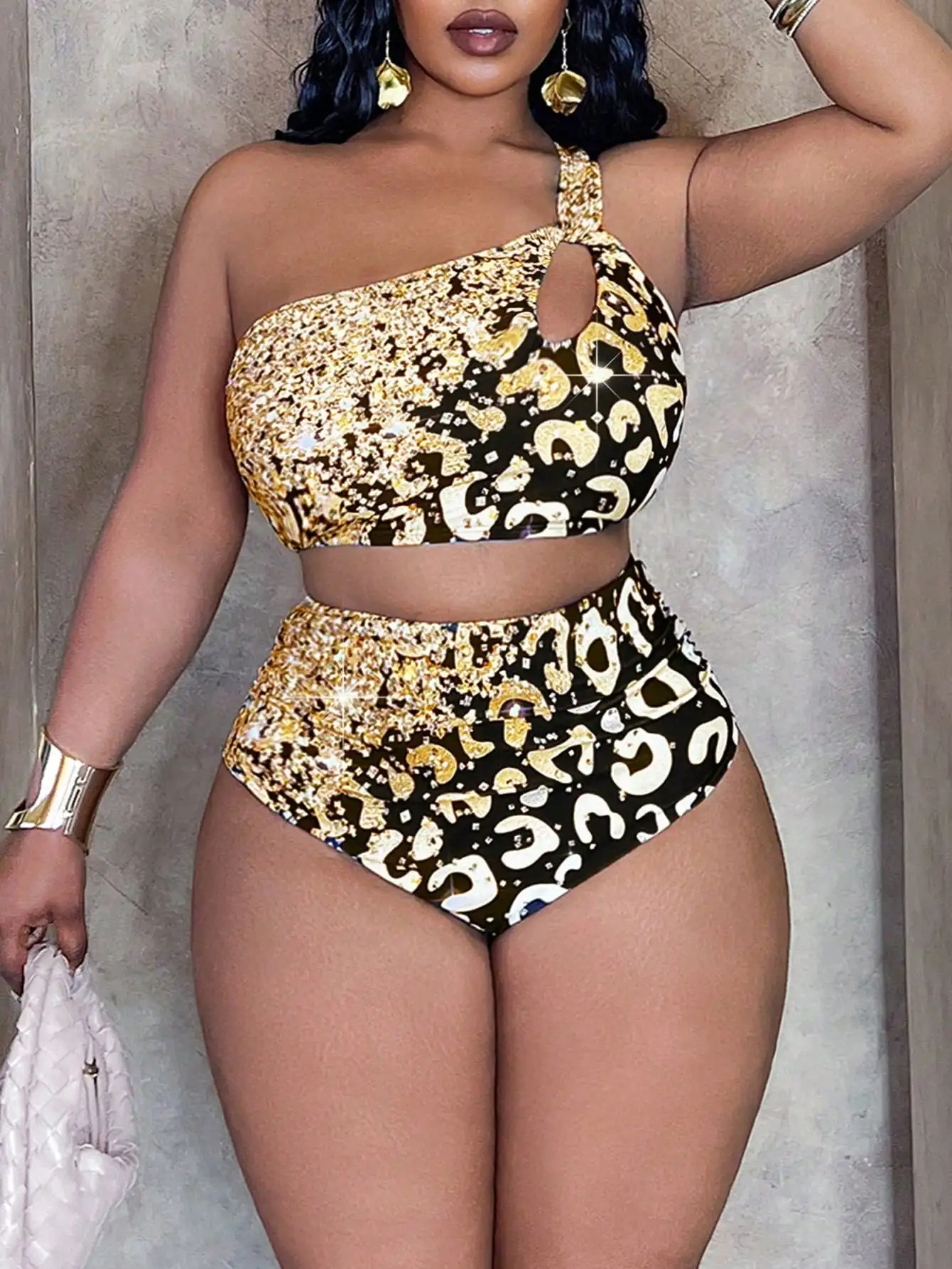 Gold Leopard Print Halter Bikini Set 4 | PricZone Woman in a gold and black animal print one shoulder bikini with a small chest cutout standing against a textured wall | PricZone