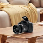 Black digital camera with a large lens rests on a wooden coffee table in a cozy living room | PricZone