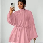 Woman in a pink long sleeve shift dress taking a mirror selfie with a silver smartphone hair in a high bun and gold hoop earrings | PricZone