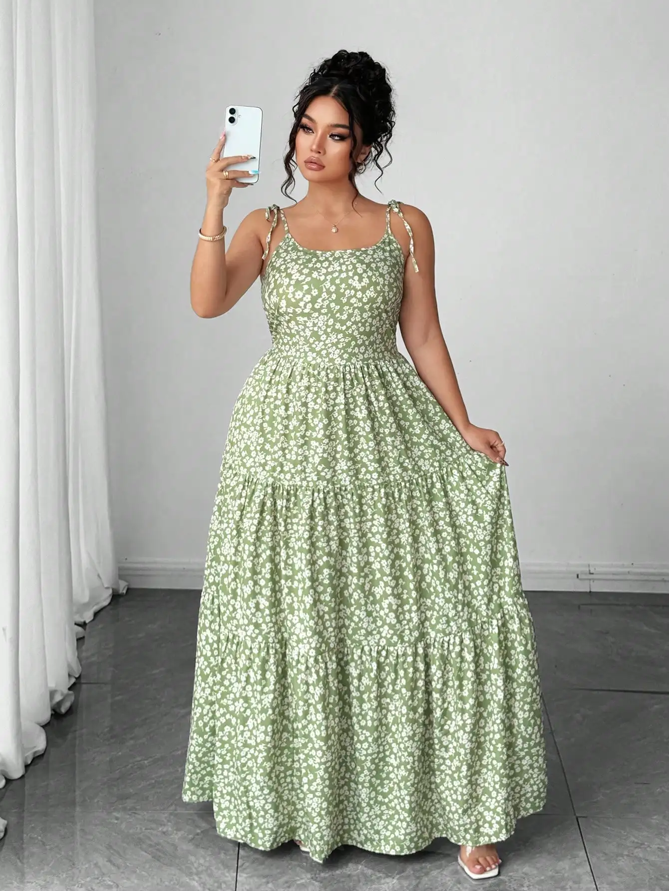 Light Green Tiny Floral Tiered Maxi Dress with Tie Shoulder 3 | PricZone Woman in a green floral maxi dress taking a selfie with a white smartphone in a bright room | PricZone