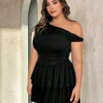 Plus Size Off Shoulder Short Summer Dress 5 | PricZone Woman in a black off shoulder dress stands against a light stone wall looking at the camera | PricZone