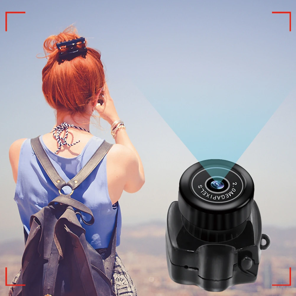 Woman with red hair and backpack seen from behind outdoors; a large wearable camera/accessory appears in the foreground, suggesting a tech promo.