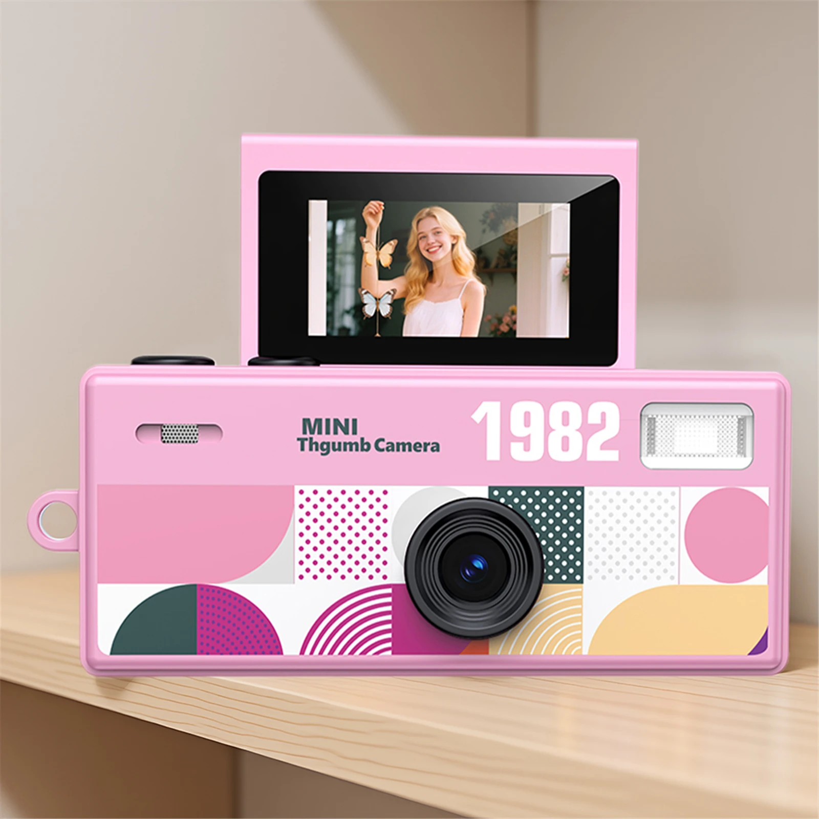 Pink retro-style mini camera with colorful geometric front panel and a small screen showing a smiling blonde woman with butterflies in the display image.] } (Note: The JSON should contain an array of strings; ensure proper formatting in your system.)