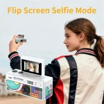 Side profile of a girl in a jacket holding a small retro mini camera with a large product box in the foreground and the text Flip Screen Selfie Mode above | PricZone