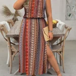 Woman in a boho patterned sleeveless maxi dress with a front slit holding a phone and a woven clutch | PricZone