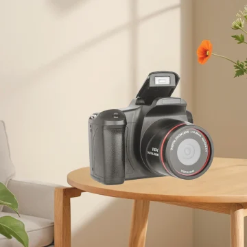 Digital camera with a flip-out screen resting on a round wooden table in a softly lit living room.