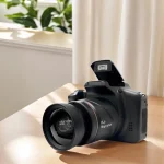DSLR camera with a wide lens and pop up flash raised on a wooden table by a window with plants in the background | PricZone