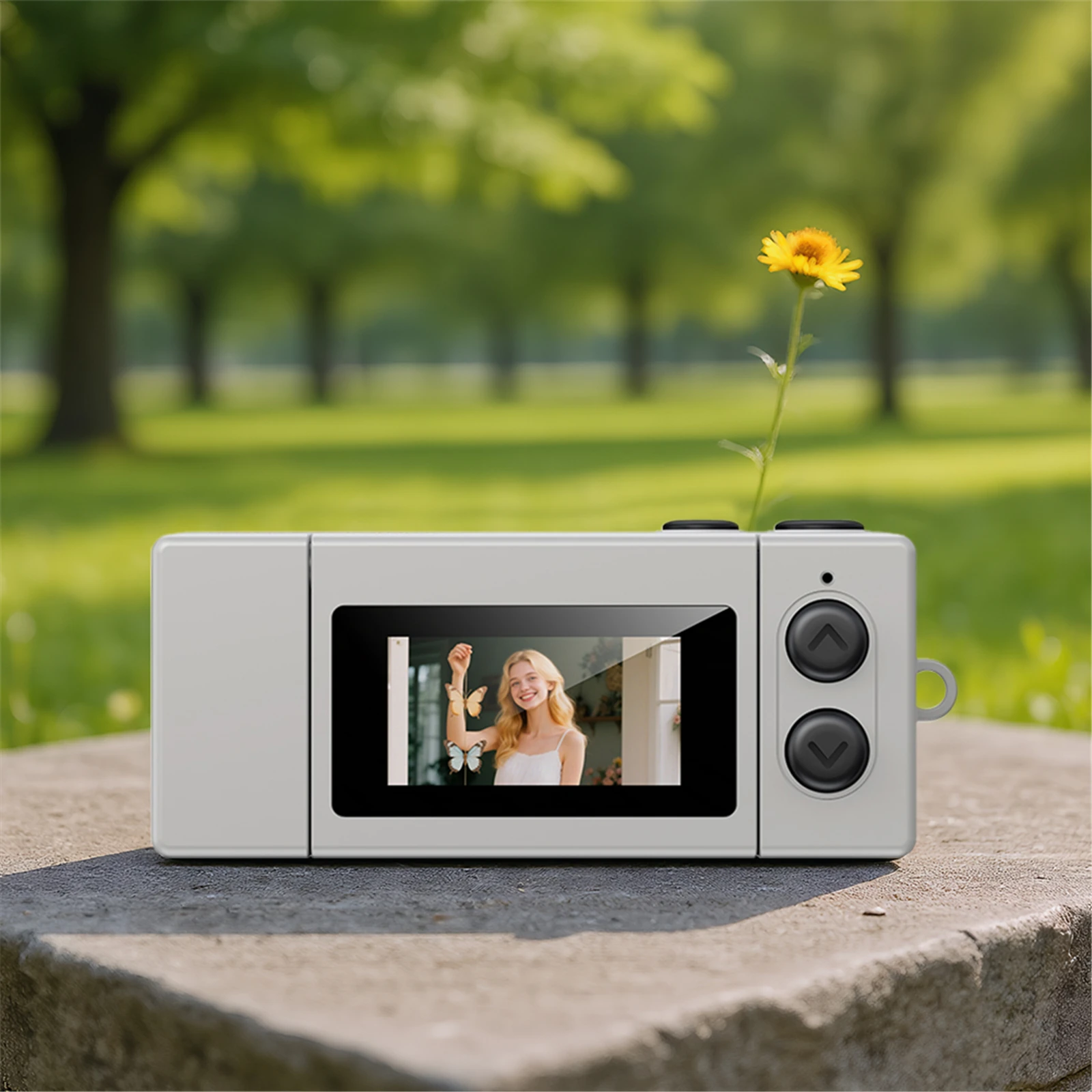 Compact camera with a yellow flower growing from its top in a sunny park setting