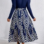 Plus Size Round Neck Long Sleeve Chevron Print Midi Dress 3 | PricZone Back view of a person wearing a navy long sleeve top and a navy and cream chevron patterned midi length skirt with a tied waistband standing against a white textured wall | PricZone
