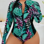 Woman in a tropical leaf print long sleeve zipper bodysuit with hoop earrings posed outdoors | PricZone