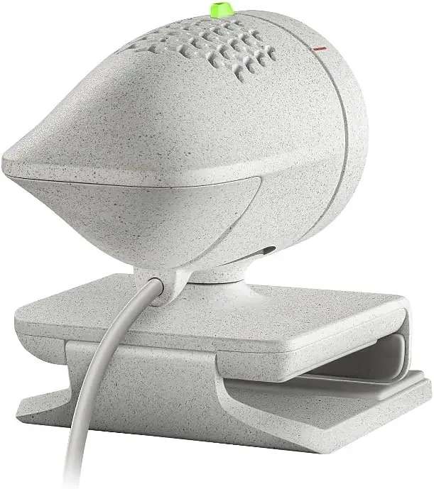 Medical device with a rounded, vented head on a stand, connected by a cord. The speckled white instrument sits on a rectangular cradle with a small green top knob.