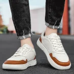 White sneakers with brown accents worn with rolled jeans on a paved street | PricZone