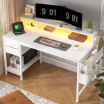 White desk workspace with dual monitors a laptop showing a green battery icon keyboard and mouse and a plant nearby | PricZone