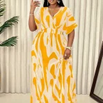 Plus Size Tropical Leaf Print Summer Maxi Dress 2 | PricZone Woman in a bold yellow and cream abstract print maxi dress takes a selfie holding a white smartphone in front of a light backdrop | PricZone