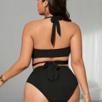 Black Plus Size Halter One Piece Swimsuit with Side Cutouts 2 | PricZone Woman wearing a black halter bikini from the back tie knot at neck and waist with gold jewelry visible on her left wrist and ear | PricZone