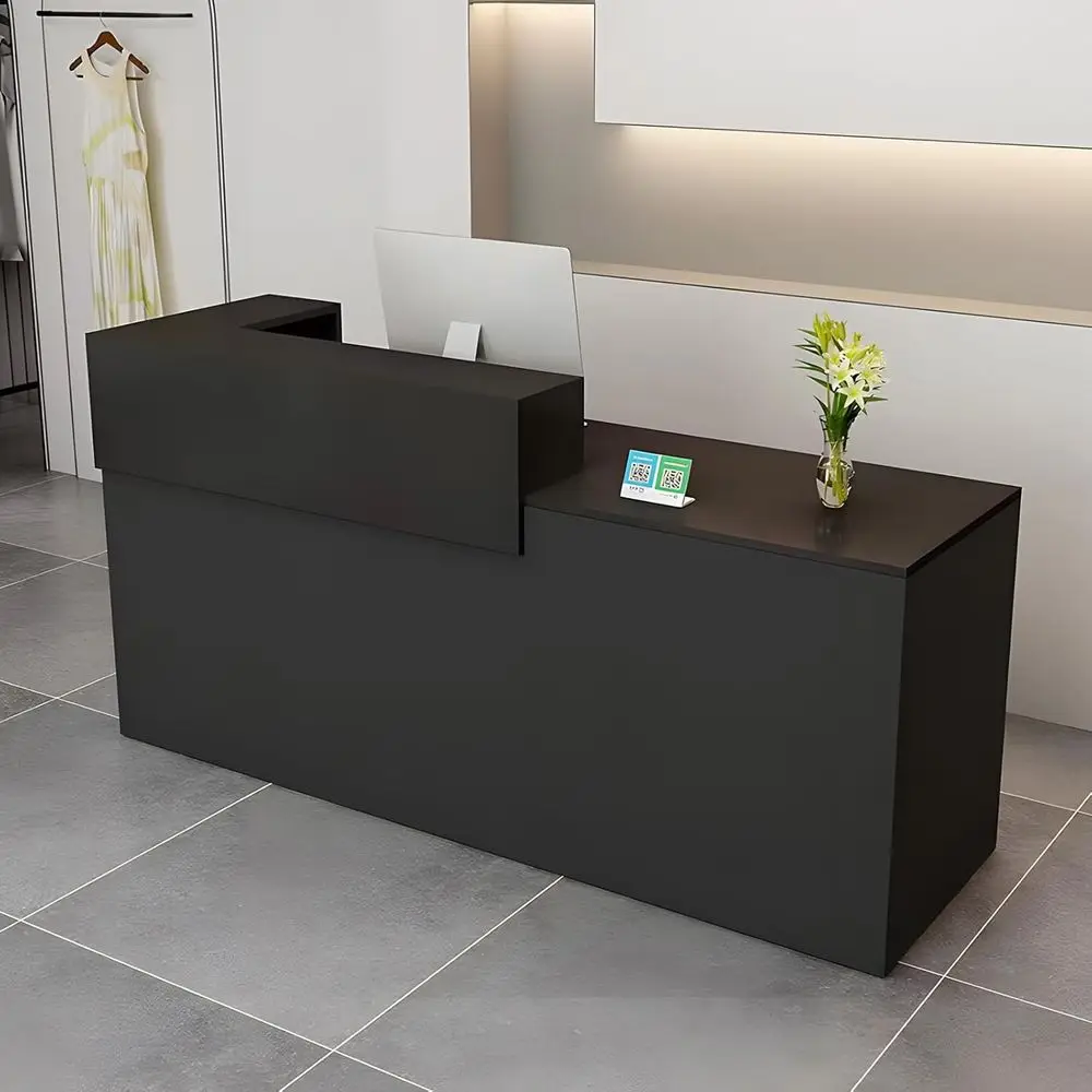 Adjustable Height Desk with Storage and Open Shelves 3995 1 | PricZone Modern black reception desk in a clean showroom with a computer monitor QR code card and a vase of white flowers on the counter clothing on a rack to the left | PricZone