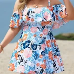 Woman wearing a colorful tropical floral off shoulder dress at the beach accessorized with layered necklaces and bracelets | PricZone