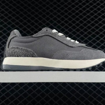Gray sneaker on a white shelf side view with white laces against a dark grid background showcasing a retro running shoe style | PricZone