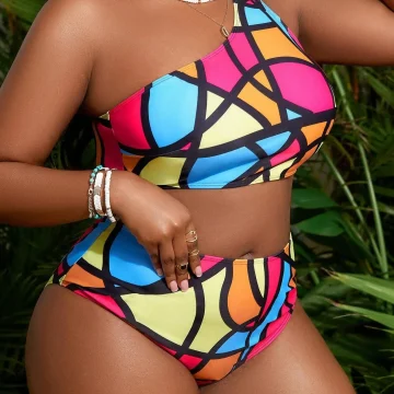 Woman in a bright, geometric-pattern bikini with a one-shoulder top, accessorized with white beads and bracelets, outdoors among greenery.