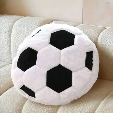 Round plush soccer ball pillow resting on a beige couch.