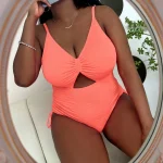 Plus Size Cut Out Swimsuit with Drawstring Side 5 | PricZone Woman in a coral pink one piece swimsuit with a knot cutout taking a mirror selfie with a phone wearing a necklace and bracelet | PricZone