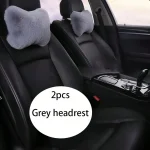 Two grey plush headrest cushions on the front car seats inside a black sedan with a circular label reading 2pcs Grey headrest | PricZone