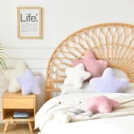 Bedroom scene with a wicker headboard pastel star pillows on the bed and a framed Life poster on the wall | PricZone