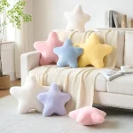 Pastel star shaped cushions scattered on and around a cream sofa in a cozy living room with a white throw blanket and plant nearby | PricZone