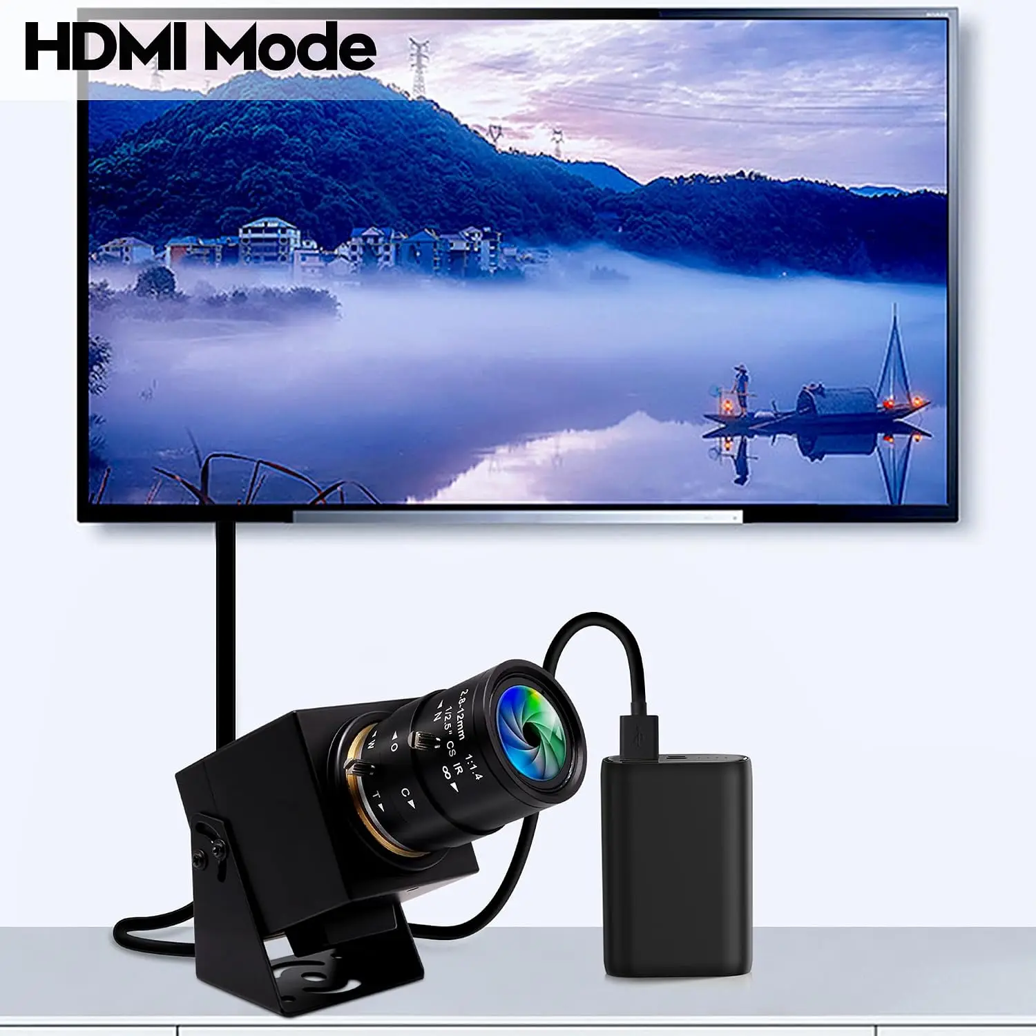 Monitor displays a landscape image with a bold 'HDMI Mode' label; a camera lens mount and USB power brick sit below, connected by cables, on a clean surface.