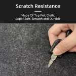 Hand holding a key with a black clip on a dark felt surface to illustrate scratch resistant material quality as shown by the text above | PricZone