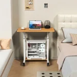 Adjustable Height Standing Desk with Wheels for Home Office 6 | PricZone Bedroom workstation wooden desk with laptop a cup of coffee and a transparent desktop PC case beneath the desk beside a white bed | PricZone