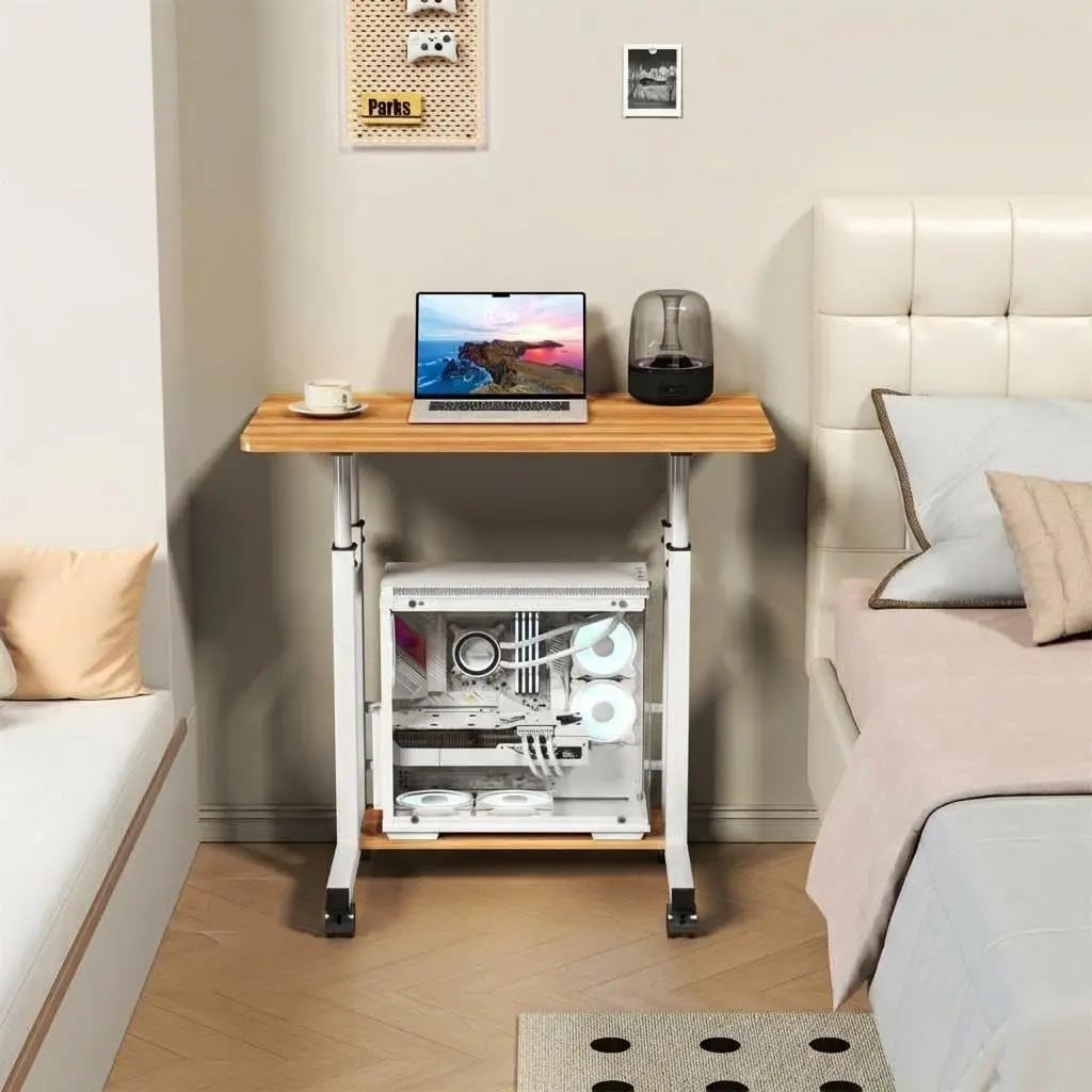 Adjustable Height Standing Desk with Wheels for Home Office 6 | PricZone Bedroom workstation wooden desk with laptop a cup of coffee and a transparent desktop PC case beneath the desk beside a white bed | PricZone