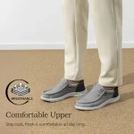 Feet in gray slip on sneakers on a tan floor Breathable badge and Comfortable Upper slogan | PricZone