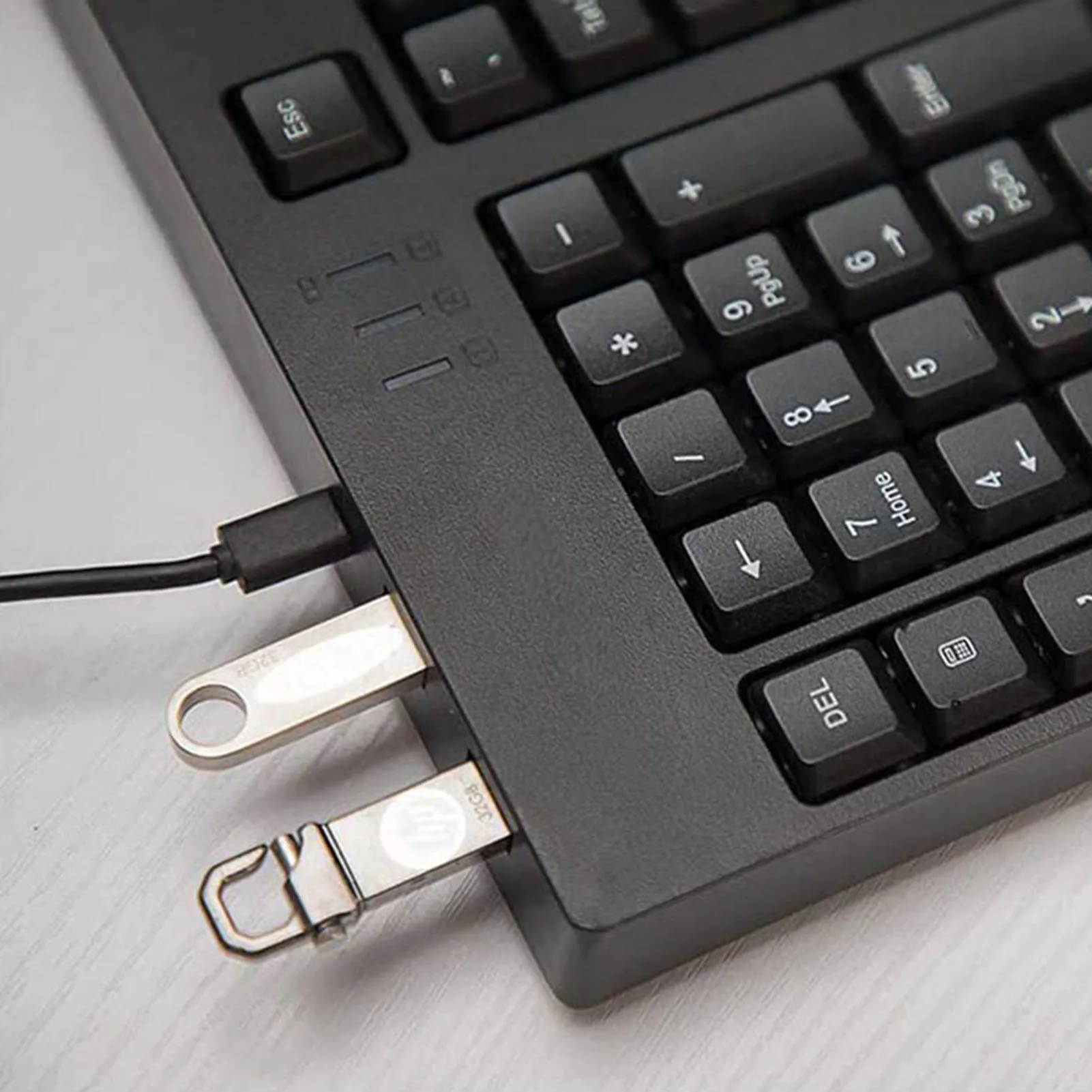 Close-up of a laptop keyboard with two USB flash drives plugged into the side ports.