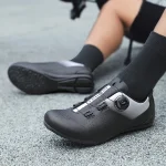 Close up of a black and gray cycling shoe with a BOA dial fastening on a gray pavement surface | PricZone