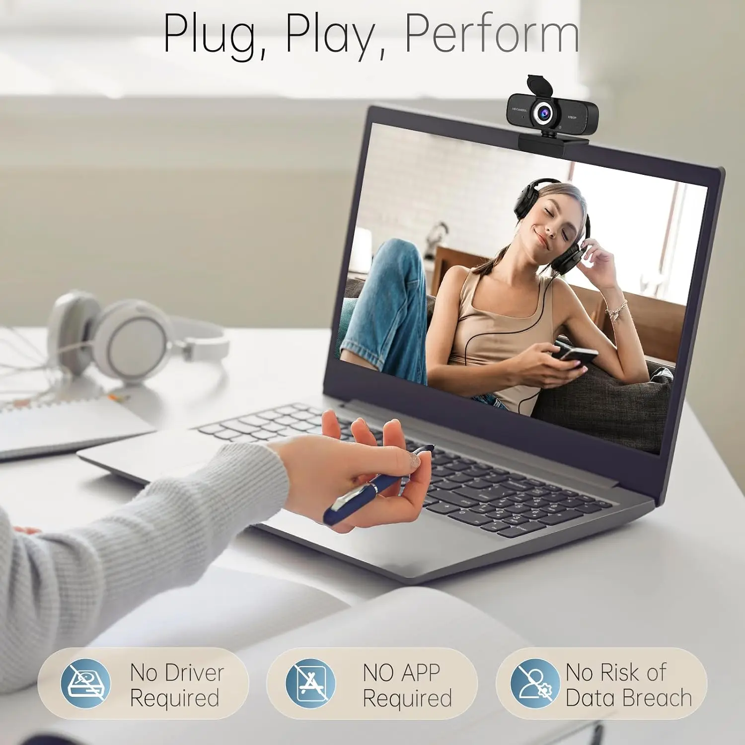 Laptop with a webcam mounted on top; on-screen person wearing headphones, banner reads 'Plug, Play, Perform'
