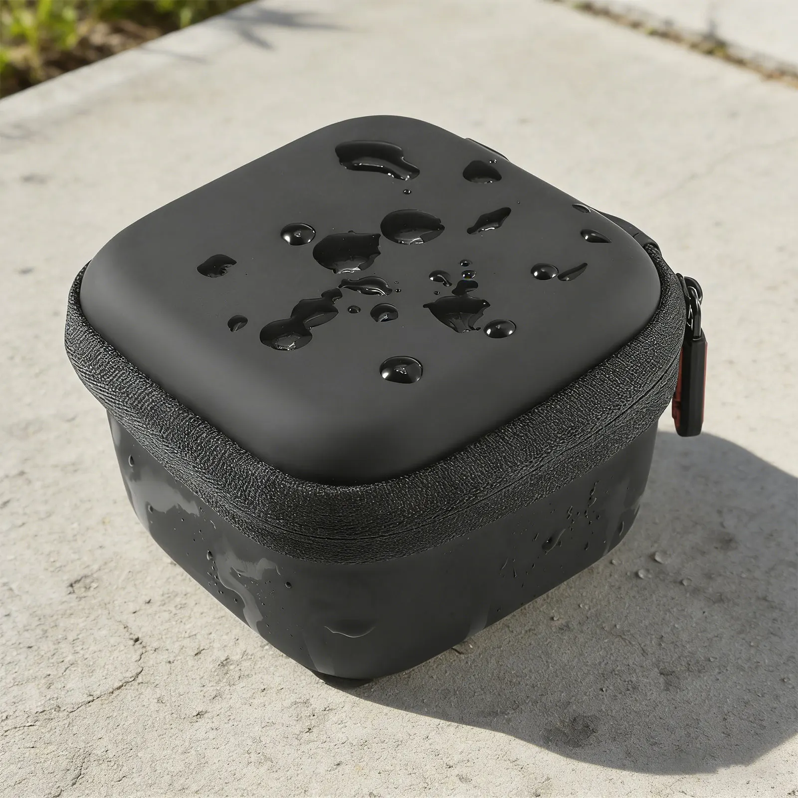 Close-up of a black cylindrical water bottle with droplets on its top, resting on a concrete surface.