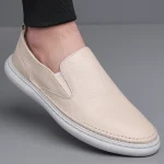 Beige slip on leather shoe with a white sole on a foot showing a textured pebble grain finish | PricZone