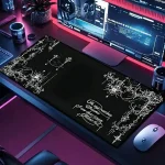 Dark desk setup with a large black decorative desk mat featuring white floral borders and script text under a curved multi monitor workstation with neon lighting | PricZone