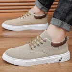 Beige low top canvas sneakers with white chunky sole brown heel patch and metal eyelets worn with rolled jeans on a wooden floor | PricZone