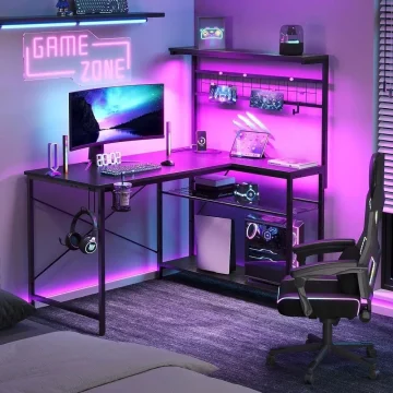 Modern gaming desk setup with neon purple lighting, monitor, keyboard, headphones, and a comfortable chair.