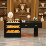 Jewelry store interior with a black display counter glass cases of rings and bracelets and white busts on golden shelves in warm lighting | PricZone